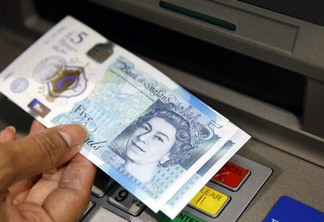 In this Sept. 13, 2016 file photo, a member of staff at a branch of Halifax bank, in London, displays a new British 5 pound sterling note, made from polymer, which is being launched Tuesday.  The beleaguered British pound plummeted briefly to a fresh 31-year low Friday, Oct. 7, 2016,  amid intensifying concerns about Britain's exit from the European Union. The pound tumbled nearly 6 percent in early Asian trading, falling as low as $1.1789, according to FactSet data.